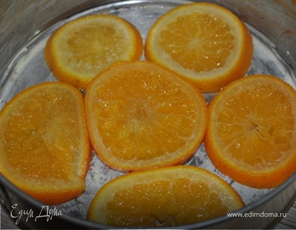 Апельсины порезать кружечками, залить водой, всыпать сахар и поставить на огонь. Довести до кипения и варить на медленном огне 20 минут. Сироп слить.
Выбрать самые красивые кружечки и уложить их на дно смазанной маслом разъемной формы (20-22 см. в диаметре).