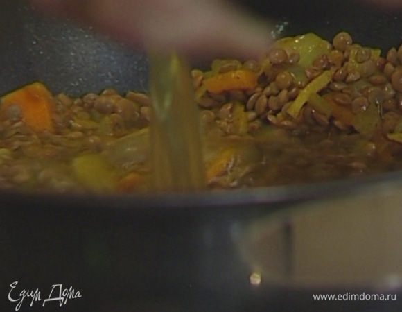 Всыпать чечевицу, еще раз перемешать и влить горячий бульон, так чтобы чечевица была полностью покрыта жидкостью.  