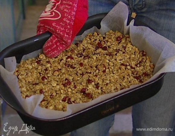 Выстелить противень бумагой для выпечки, смазать ее оставшимся сливочным маслом. Выложить хлопья на противень, распределить ровным слоем и выпекать в разогретой духовке 25−30 минут. 