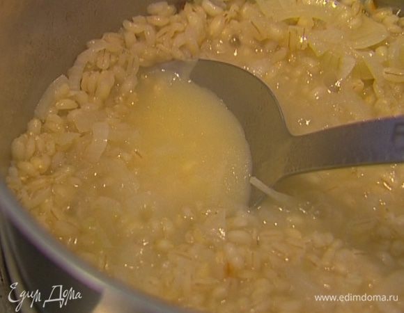 Добавить перловку, перемешать, влить 50 мл вина и горячий бульон, накрыть крышкой и варить крупу до готовности. 