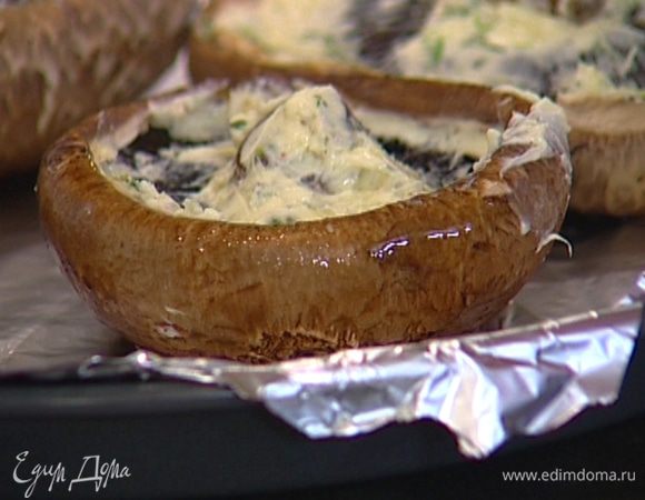 Внутреннюю сторону шляпок грибов смазать пряным маслом, выложить их на противень, выстеленный фольгой, влить оставшееся вино, накрыть сверху фольгой и запекать в разогретой духовке 25‒30 минут. 