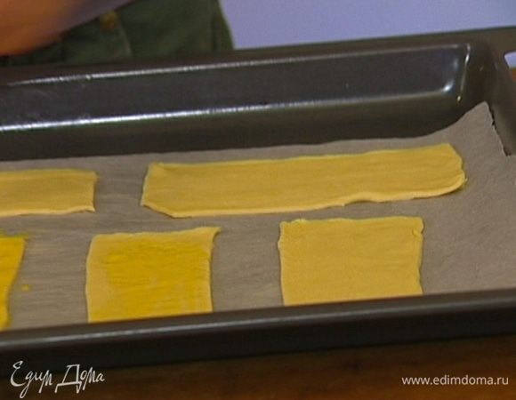 Нарезать охлажденное тесто небольшими прямоугольниками, так чтобы получилось четное количество, и выложить на противень, выстеленный бумагой для выпечки.