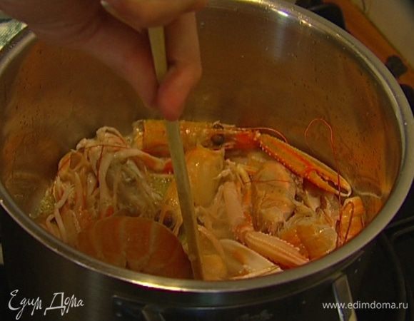 Разогреть в тяжелой кастрюле 1 ст. ложку оливкового и 1 ст. ложку сливочного масла, выложить панцири, головы, клешни лангустинов и слегка размять деревянной лопаткой.