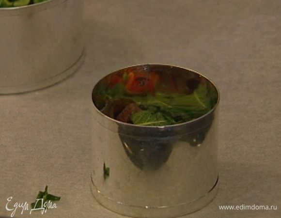 Выстелить противень бумагой для выпечки, разложить на нем круглые формочки-кольца без дна и наполнить каждую формочку салатом примерно до половины.