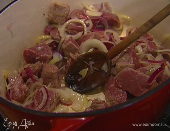 Мясо порезать крупными кубиками, выложить в кастрюлю к луку и чесноку, перемешать и обжарить до легкого золотистого цвета.