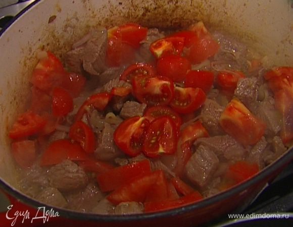 Помидоры крупно нарезать, отправить к мясу и томить все вместе 10‒15 минут на небольшом огне.