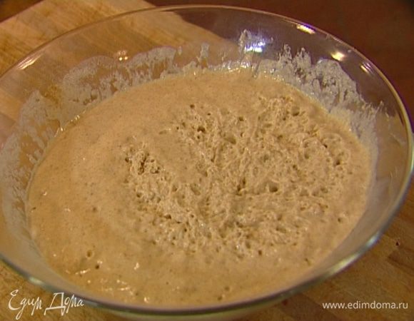 Добавить опару и, непрерывно вымешивая, частями влить около 300 мл теплой воды — тесто не должно быть слишком густым. Накрыть посуду с тестом влажным полотенцем и поставить в теплое место на 30 минут.