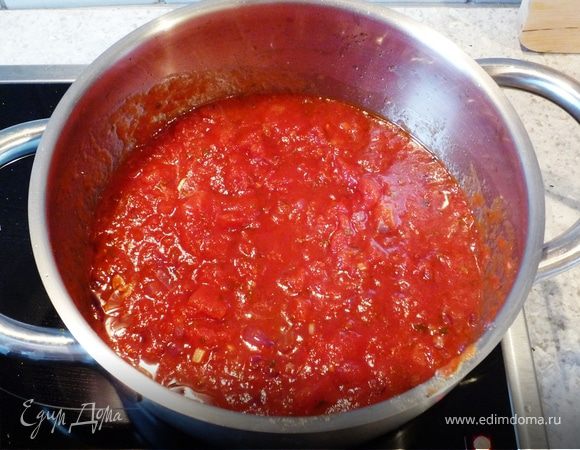Тем временем для соуса мелко нарежем лук и чеснок. В кастрюле разогреваем масло и обжариваем лук, затем добавляем чеснок и еще обжарим 1 минуту. Добавляем
томаты в собственном соку, рубленый базилик, соль, перец. Доводим соус до кипения...
