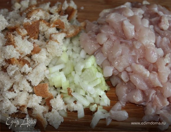 Куриное филе как можно мелче порезать. Чеснок раздавить ножом и порезать. Лук измельчить. Хлеб порезать кубиками. Его должно получиться по объему столько же, сколько куриного фарша.