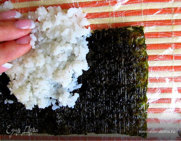 На лист раскладываем рис тонким слоем с небольшим усилием, так чтобы он прилипал к листу нори равномерно.