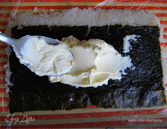 Переворачиваем нори рисом вниз и смазываем лист сыром филадельфия (в середине как можно больше)