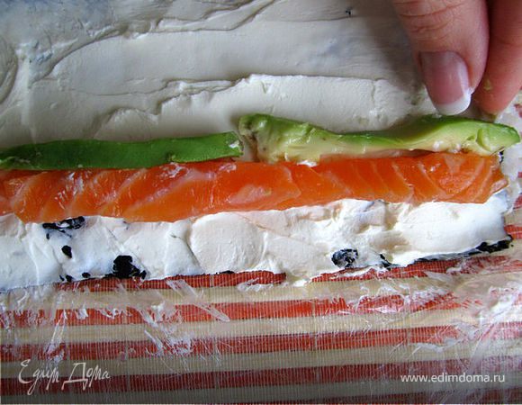 На сыр выкладываем рыбу и порезанное авокадо ближе к краю листа(авокадо можно заменить огурцом)