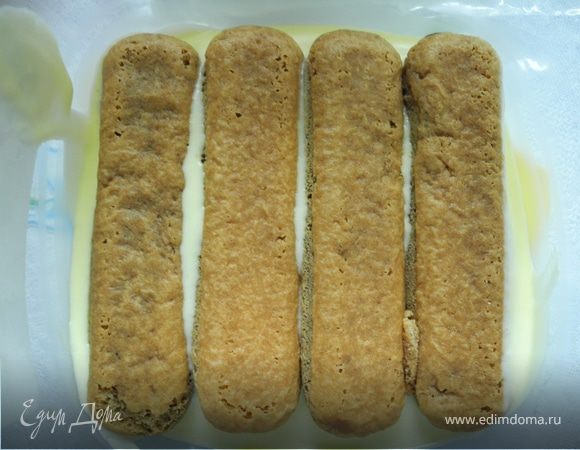 На дно формы положить немного крема.
Печенье смочить в кофе и выложить поверх крема.
