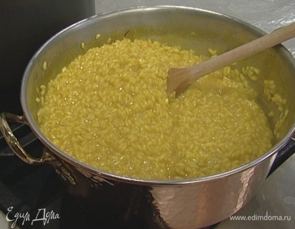 Влить вино и через 1 минуту начать добавлять бульон, половник за половником, позволяя рису впитывать жидкость.