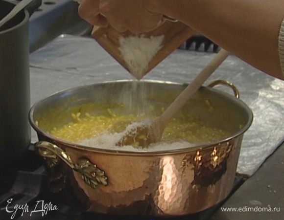 Через 18‒20 минут, когда рис будет почти готов, добавить замоченный в бульоне шафран, оставшееся сливочное масло и половину натертого сыра. На 1 минуту закрыть сковороду крышкой и затем очень энергично все перемешать, почти взбить.