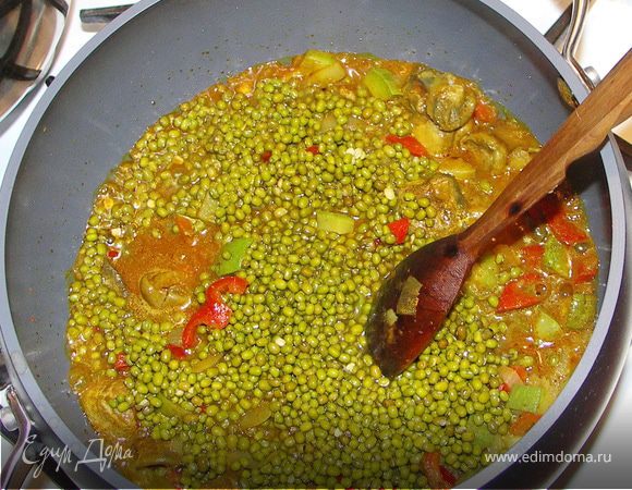 Добавляем половину наших пряностей к овощам.Туда же высыпаем маш.Заливаем 1,5 стакана овощного бульона или кипятка.Закрываем крышкой и ставим на умеренный огонь минут на 15-20.