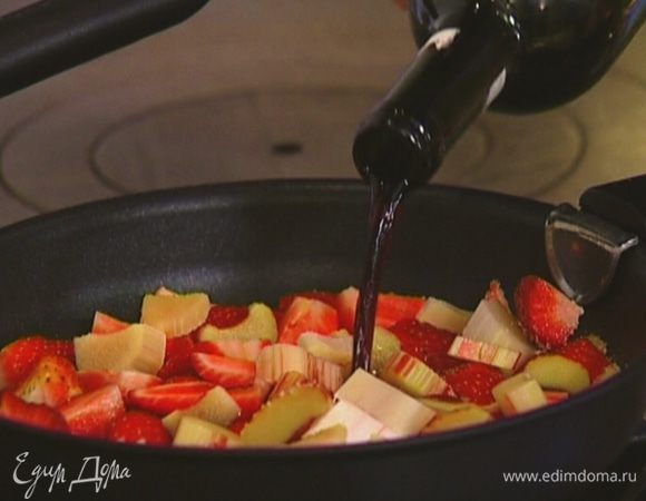 Приготовить соус: разогреть тяжелую сковороду, всыпать в нее сахар, добавить клубнику и ревень, влить вино. 