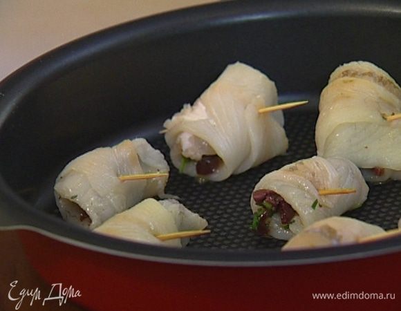 На один край полосок выложить оливковую начинку, свернуть в рулетики и скрепить зубочистками. 