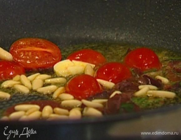 Выложить в сковороду к чесноку помидоры, оливки вместе с заправкой и кедровые орехи и обжаривать 1–2 минуты.