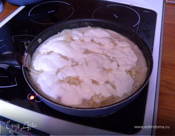 Уложить лук поверх кальмаров, залить сметаной и тушить под крышкой 10-15 минут.