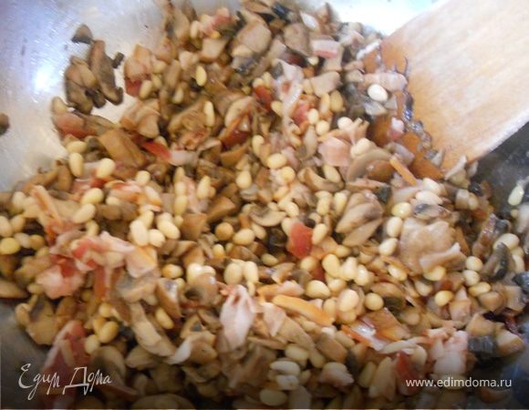 Шампиньоны (почищенные от грязи/пыли) измельчить, обжарить на сковороде  добавлением оливкового масла несколько минут, в принципе можно и не обжаривать - дело вкуса, выложить в отдельную емкость. Добавить измельченный бекон и обжаренные на сухой сковороде кедровые орешки, перемешать. 