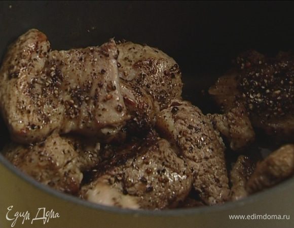 Переложить обжаренную свинину в кастрюлю, а в сковороде растопить оставшееся сливочное масло и обжарить лук до золотистого цвета.