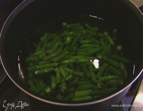 Фасоль выложить в небольшую кастрюлю, залить горячей водой и прогревать на небольшом огне 2–3 минуты, затем откинуть на дуршлаг и отправить на несколько минут в миску со льдом.