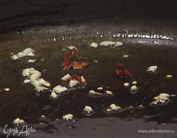 В глубокой тяжелой сковороде разогреть 2 ст. ложки оливкового масла и обжарить чеснок и чили.