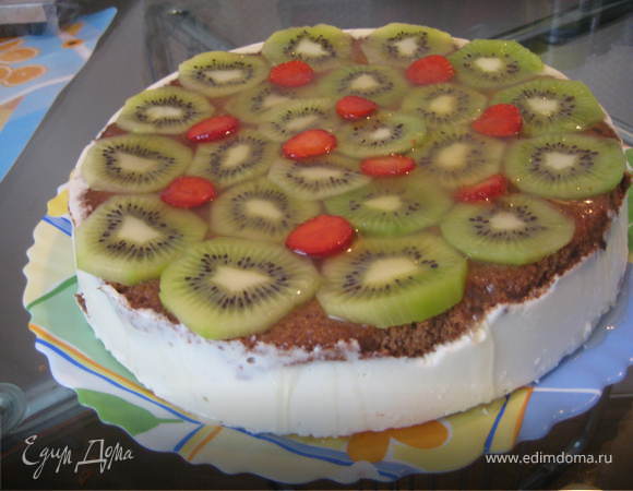 После полного застывания(около 1-2 часов) достаем торт из формы и приступаем к украшению.Киви очищаем и нарезаем кружочками,выкладываем на верхушку торта.Желе для торта готовим,согласно инструкции на упаковке на основе ананасового сока и выливаем на киви.Возвращаем торт в холодильник для застывания желе.