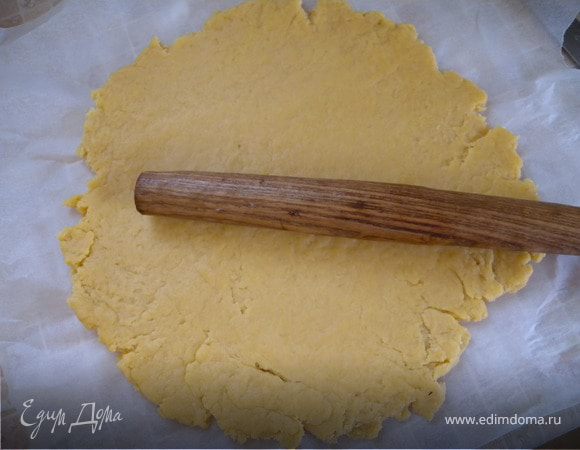 Раскатать тесто скалкой на бумаге для выпечки чуть больше размера формы для выпечки. 