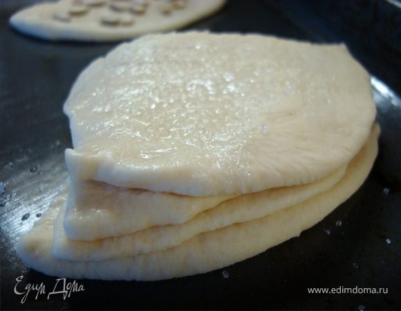 Противень смазать тонким слоем сливочного масла или маргарина. Выкладывать на него поочередно части лепешки одна на другую, при том каждую четвертинку смазывать небольшим количеством воды. Всего в каждой булочке у вас получается 4 слоя… Верхний слой также обязательно смазать водой...