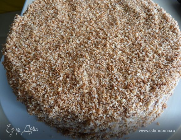 Готовим крошку для украшения: в блендере измельчить оставшиеся от коржей обрезки и грецкие орехи, получившейся крошкой обильно посыпать торт со всех сторон, обмазать боковинки. Сверху присыпать натертым замороженным шоколадом и убрать в холодильник пропитываться (минимум на 3 часа). Перед подачей можно еще посыпать тертым шоколадом. 
