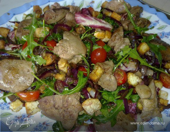 Нарежьте луковицу тонкими перьями, разогрейте в сковороде совсем немного растительного масла и начните обжаривать лук – на самом сильном огне и постоянно помешивая. Через пару минут, когда лук станет слегка прозрачным, влейте ложку бальзамического уксуса (тут можно взять самый дешевый), а если лук, по-вашему, недостаточно сладок, добавьте немного сахара. Обжаривайте, помешивая, на все том же максимальном огне до тех пор, пока уксус частично не выпарится, а частично не впитается в лук. Снимите лук с огня и дайте немного остыть. 
Для заправки смешайте масло, уксус, измельченный чеснок, посолите и поперчите. Параллельно приготовьте крутоны – тут уж ничего сложного нет, просто нарежьте подсохший белый хлеб кубиками, немного сбрызните маслом да подсушите в духовке до золотистости. Куриную печень зачистите от пленок и жилок, если печенки попались слишком большие – разрежьте пополам, затем посолите и поперчите. Если используете бекон – мелко нарежьте и вытопите из него жир, если не используйте – просто разогрейте немного растительного масла и обжарьте куриную печень на среднем огне до готовности, но не пересушивая. 
Собираем салат, пока куриная печень не успела остыть: соедините в миске салатные листья, половинки черри, “бальзамированный” лук и, если есть, бекон, затем влейте почти всю заправку и как следует перемешайте. Добавьте крутоны, снова перемешайте, разложите салат по тарелкам и выложите сверху куриную печень. Прицельно полейте ее остатками заправки, при желании приправите салат с куриной печенью свежемолотым черным перцем и немедленно подавайте. 
