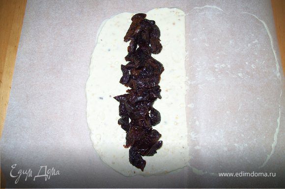 Достать шоколад из холодильника. снять верхний слой пергамента. Выложить нарезанный чернослив на середину шоколада.