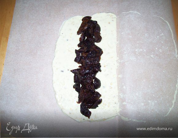Достать шоколад из холодильника. снять верхний слой пергамента. Выложить нарезанный чернослив на середину шоколада.