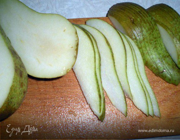 Вытаскиваем испекшееся тесто вместе с противнем из духовки, а в ней увеличиваем температуру до 200 гр.
Груши нарезать тонкими ломтиками. 