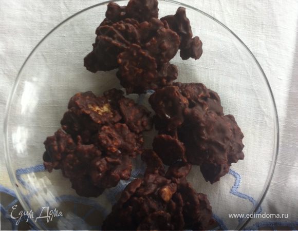 Растопить  шоколад и сливочное масло на водяной бане (я топила в микроволновке), добавить 1-2 чайные ложки  сахарного сиропа. Хорошо перемешать и добавить кукурузные хлопья (я добавила еще 3 грецких орешка). На противне расстелить лист пергамента и чайной  ложкой выложить массу небольшими кучками. Поставить противень в холодильник  на час для застывания. 
Варим кофе, чай и наслаждаемся  вкуснятиной!
Думаю в следующий раз заменить  сироп на ликер типа Бейлиз.