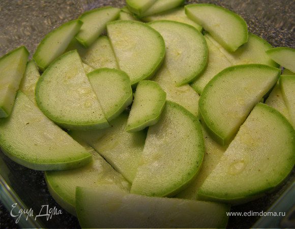 Кабачок порезать полукольцами. Выложить первым слоем в форму для выпекания. Посолить, поперчить.