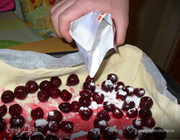 Включить духовку на 180 градусов. Распаковать замороженную вишню и высыпать ее на тесто.
Посыпать вишню сахарной пудрой - это ответственное дело я доверила мужу))