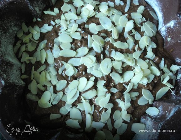 Затем добавить какао и в самом конце ввести белки, очень осторожно вмешивая. Форму смазать сливочным маслом и присыпать мукой. Вылить тесто. Сверху посыпать миндальными лепестками. 