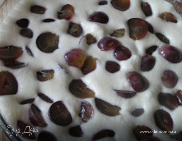 Форму для выпечки смазать маслом, вылить половину теста, разложить виноград...