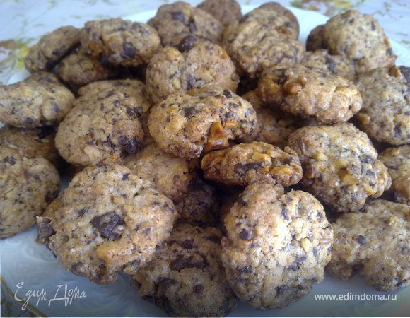 Духовку разогреть до 180° С. 

Противень ( один или два - смотрите сами) устелить пергаментной бумагой. 

Взбить миксером на средней скорости сливочное масло, сахар и ванильную эссенцию. У вас должна получиться светлая кремообразная масса. Добавьте яйцо, затем муку с разрыхлителем и на низкой скорости всё взбейте немного. У вас получится крошка. 
Добавьте грецкие орехи, шоколад. Размешайте всё с помощью деревянной ложки. 
Сильно не мешайте и не взбивайте.  

Сформируйте 32 шарика, слегка прижмите сверху и выложите их на противень. Между шариками должно быть расстояние примерно 2 см. 
Выпекайте в течении 15 минут. 
