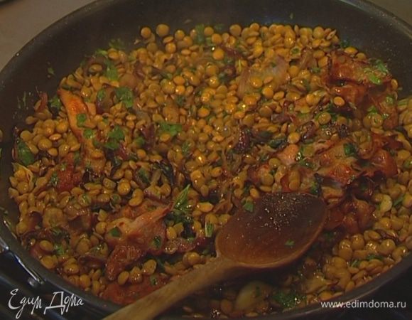 Выложить чечевицу в сковороду к луку с беконом, влить немного воды, в которой она варилась, поставить сковороду на огонь, заправить оливковым маслом, посолить, поперчить и немного прогреть. Выключить огонь и  оставить чечевицу на некоторое время в сковороде, чтобы она пропиталась запахами лука и бекона. 