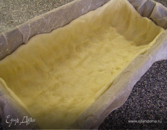 Форму для выпекания выстелить пекарской бумагой. Распределить тесто по форме, сделав бортики. Отправить в холодильник минимум на час. 
Духовку разогреть до 180 градусов. Выпекать корж минут 13-15 до лёгкого золотистого цвета.