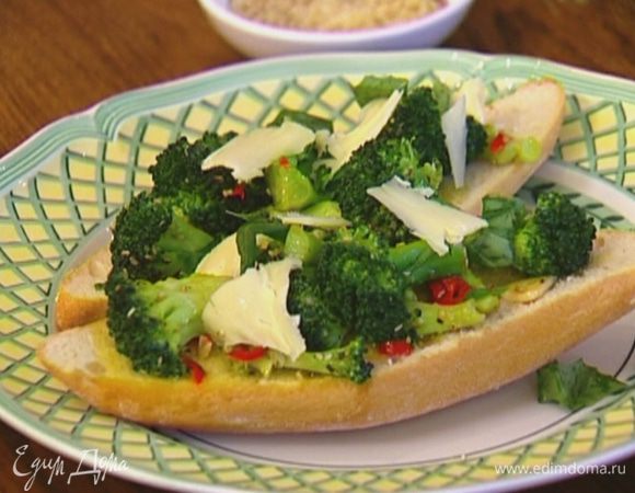 На обжаренные ломтики хлеба выложить брокколи, присыпать сырными хлопьями и украсить листьями базилика.