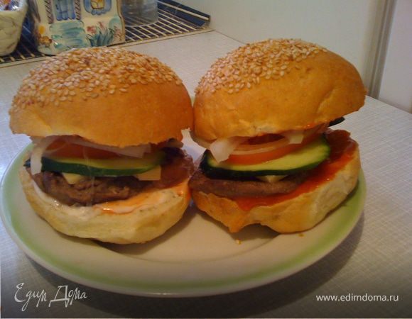 Фарш для котлет: в фарш (покупаем или пропускаем через мясорубку любимое мясо – говядина, свинина, баранина, курятина и т.д., добавляем яйцо, размоченный в молоке подсохший кусочек хлеба) добавляем соль, перец, специи любые (какие есть дома или какие нравятся). Формируем круглые котлетки, обжариваем на масле.

Собираем гамбургер: разрезаем булочку вдоль, нижнюю часть смазываем кетчупом, майонезом, чесночным соусом (опять же всё по вкусу) и складываем красиво и вкусно сыр, котлетку, огурчик (свежий или соленый), томат, лук.
