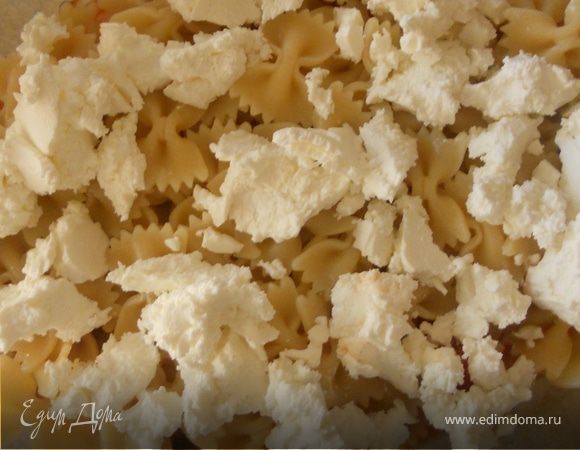 На дно жаропрочной формы выложить часть томатного соуса (примерно 1/4 или чуть больше). Разместить половину пасты, поверх раскрошить фету и снова оставшуюся пасту.