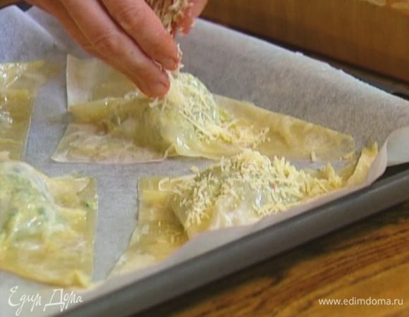 Противень выстелить бумагой для выпечки, выложить пирожки, смазать их оставшимся сливочным маслом и посыпать натертым сыром.