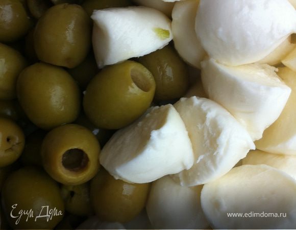 С оливок слить воду, шарики моцареллы разрезать пополам.