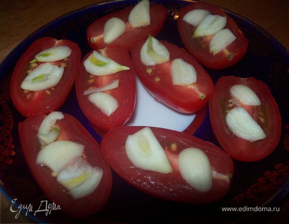Помидоры помыть, обсушить, разрезать вдоль. Сверху на помидоры выложить тонко нарезанный чеснок и сбрызнуть оливковым маслом.